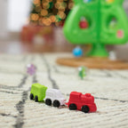 Grüner interaktiver Weihnachtsbaum mit bunten Spielelementen und kleiner Spielzeugeisenbahn