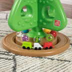 Grüner interaktiver Weihnachtsbaum mit bunten Spielelementen und kleiner Spielzeugeisenbahn