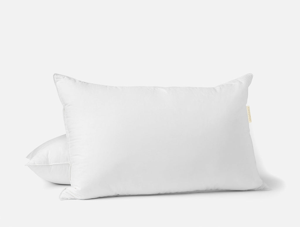 Weißes Kopfkissen mit Daunenfedern auf einem Bett