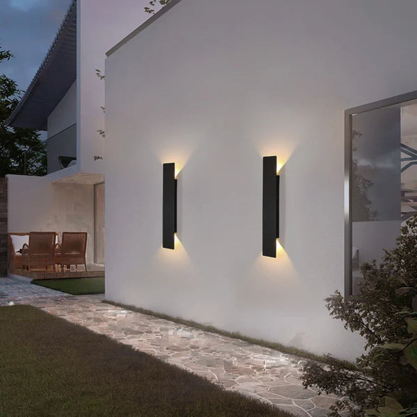 Schwarze vertikale LED-Außenwandleuchte mit warmweißem Licht an einer Fassade