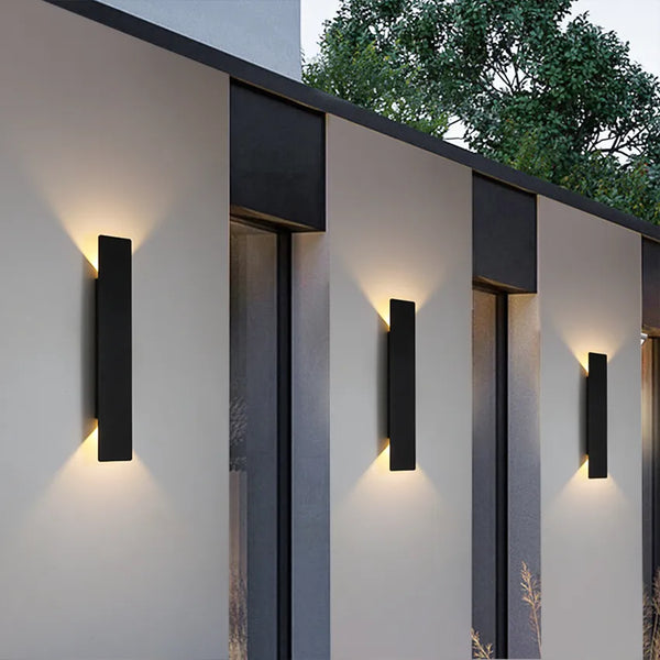 Schwarze vertikale LED-Außenwandleuchte mit warmweißem Licht an einer Fassade