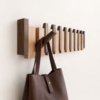 Wandgarderobe aus Holz mit mehreren Klapphaken in hellen und dunklen Holztönen